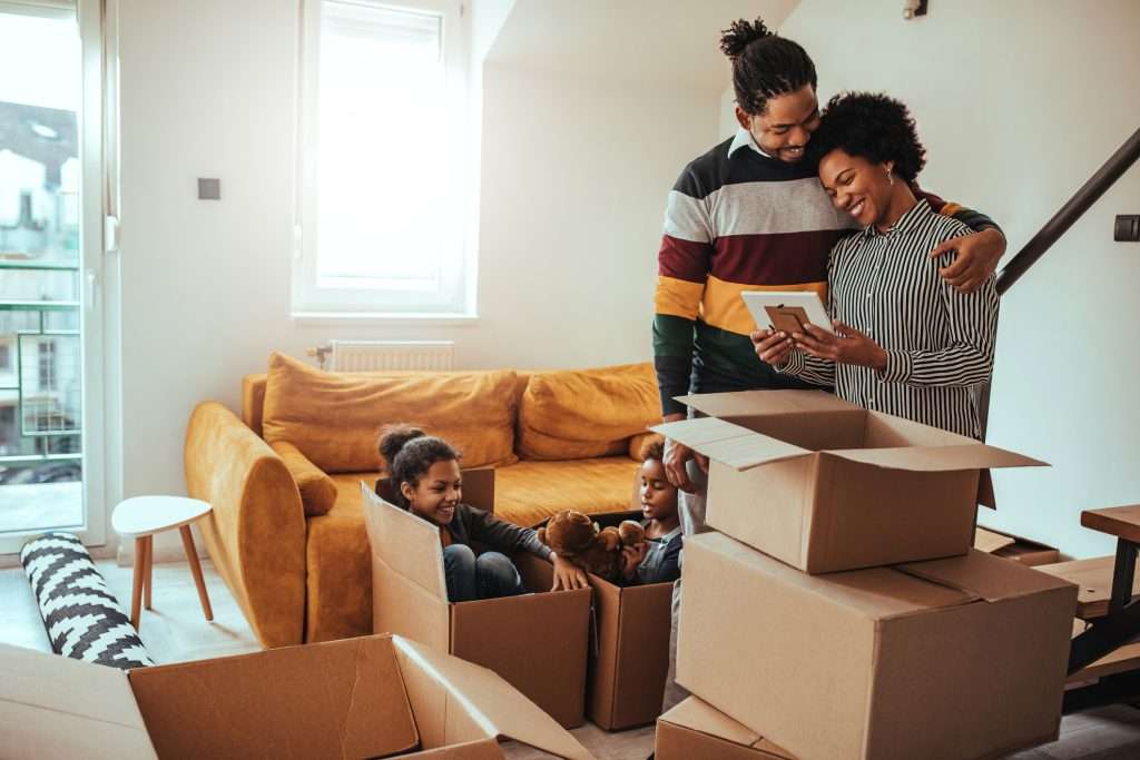 Black family unpacking boxes in new house while looking at picture
