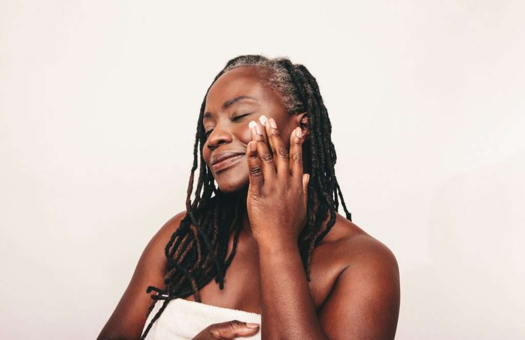 Confident dark-skinned digital nomad taking care of her flawless melanated skin.