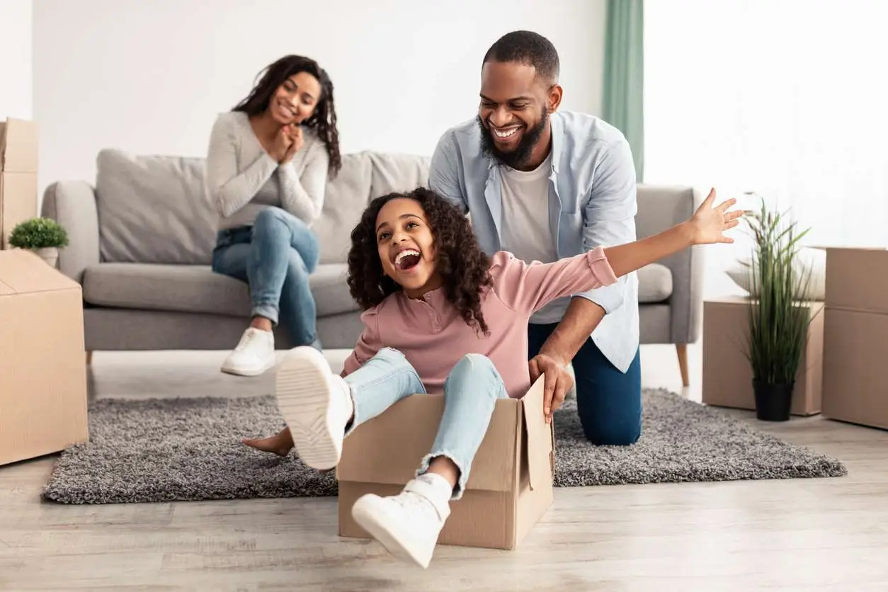 Black family of three people having fun in the living room.